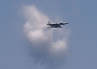 2. United States Navy F/A-18 Hornet Fighter Jet. July 26, 2003 Atlantic Ocean. Reaching the sound barrier, breaking the sound barrier: Flying at transonic speeds (flying transonically) -- speeds varying near and at the speed of sound (supersonic) -- speeds can generate impressive condensation clouds caused by the Prandtl-Glauert Singularity. For a scientific explanation, see Professor M. S. Cramer's Gallery of Fluid Mechanics, Prandtl-Glauert Singularity at <http://www.GalleryOfFluidMechanics.com/conden/pg_sing.htm>; and Foundations of Fluid Mechanics, Navier-Stokes Equations Potential Flows: Prandtl-Glauert Similarity Laws at <http://www.Navier-Stokes.net/nspfsim.htm>. Photo Credit: Photographer's Mate 2nd Class Danny Ewing Jr., Navy NewsStand - Eye on the Fleet Photo Gallery (http://www.news.navy.mil/view_photos.asp, 030726-N-4953E-081), United States Navy (USN, http://www.navy.mil), United States Department of Defense (DoD, http://www.DefenseLink.mil or http://www.dod.gov), Government of the United States of America (USA).
