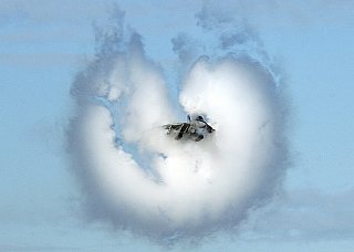 5. An F-14 Tomcat Fighter Jet Assigned to the 'Jolly Rogers' of Fighter Squadron One Zero Three (VF-103), September 26, 2002, United States Navy. Reaching the sound barrier, breaking the sound barrier: Flying at transonic speeds (flying transonically) -- speeds varying near and at the speed of sound (supersonic) -- can generate impressive condensation clouds caused by the Prandtl-Glauert Singularity. For a scientific explanation, see Professor M. S. Cramer's Gallery of Fluid Mechanics, Prandtl-Glauert Singularity at <http://www.GalleryOfFluidMechanics.com/conden/pg_sing.htm>; and Foundations of Fluid Mechanics, Navier-Stokes Equations Potential Flows: Prandtl-Glauert Similarity Laws at <http://www.Navier-Stokes.net/nspfsim.htm>. Photo Credit: Journalist 2nd Class David Valdez, Navy NewsStand - Eye on the Fleet Photo Gallery (http://www.news.navy.mil/view_photos.asp, 020926-N-2781V-170), United States Navy (USN, http://www.navy.mil), United States Department of Defense (DoD, http://www.DefenseLink.mil or http://www.dod.gov), Government of the United States of America (USA).