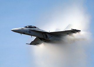 9. An F/A-18F Super Hornet Fighter Jet, September 25, 2004. United States Navy. Naval Air Station Oceana, Commonwealth of Virginia, USA. Reaching the sound barrier, breaking the sound barrier: Flying at transonic speeds (flying transonically) -- speeds varying near and at the speed of sound (supersonic) -- can generate impressive condensation clouds caused by the Prandtl-Glauert Singularity. For a scientific explanation, see Professor M. S. Cramer's Gallery of Fluid Mechanics, Prandtl-Glauert Singularity at <http://www.GalleryOfFluidMechanics.com/conden/pg_sing.htm>; and Foundations of Fluid Mechanics, Navier-Stokes Equations Potential Flows: Prandtl-Glauert Similarity Laws at <http://www.Navier-Stokes.net/nspfsim.htm>. Photo Credit: Photographer's Mate 2nd Class Daniel J. McLain, Navy NewsStand - Eye on the Fleet Photo Gallery (http://www.news.navy.mil/view_photos.asp, 040925-N-0295M-108), United States Navy (USN, http://www.navy.mil), United States Department of Defense (DoD, http://www.DefenseLink.mil or http://www.dod.gov), Government of the United States of America (USA).