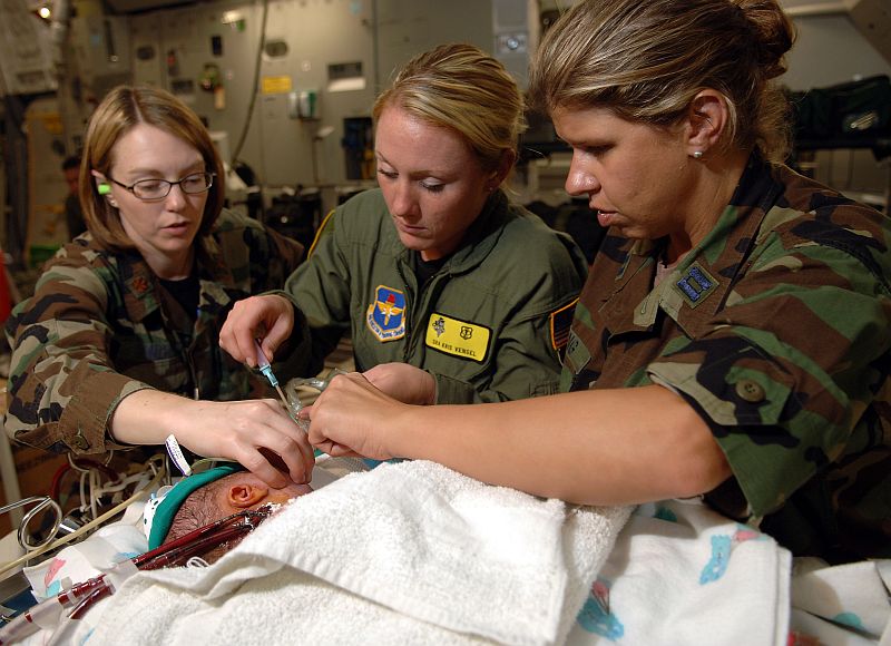 Saving Hands. Healing Hands. Four visible hands belonging to personnel with the Extracorporeal Membrane Oxygenation (ECMO) team are giving medication to a newborn. The 4-day-old baby is safely aboard the enormous USAF C-17 Globemaster III aircraft. He is in the care of the large ECMO medical team specifically sent from United States Air Force 59th Medical Wing, Wilford Hall Medical Center (located at Lackland Air Force Base, Texas, USA) to Commonwealth of Puerto Rico (USA) to bring him to San Antonio, Texas, USA, for specialized care. July 21, 2006, Aboard the C-17 Globemaster III Military Transport. Read the full story at "Medical team transports newborn from Puerto Rico" <http://www.af.mil/news/story.asp?storyID=123024023>, with additional photographs at <http://www.af.mil/news/story_media.asp?storyID=123024023>. Photo Credit: Master Sgt. Scott Reed, United States Air Force; Air Force Link - Week in Photos, July 28, 2006 (http://www.af.mil/weekinphotos/060728-03.html and http://www.af.mil/weekinphotos/wipgallery.asp?week=178, 060721-F-4884R-109, "ECMO medical team transports newborn"), United States Air Force (USAF, http://www.af.mil), United States Department of Defense (DoD, http://www.DefenseLink.mil or http://www.dod.gov), Government of the United States of America (USA). C-17 Globemaster III fact sheets from the United States Air Force <http://www.af.mil/factsheets/factsheet.asp?fsID=86> and The Boeing Company <http://www.boeing.com/defense-space/military/c17/index.htm>.