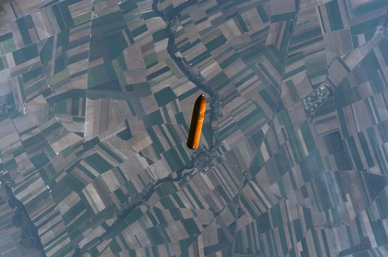 26. The Orange External Fuel Tank -- Backdropped By the Agricultural Fields of Nuisement-sur-Coole In the Champagne-Ardenne Region of France -- Falls Towards Earth After Separating From Space Shuttle Atlantis, September 9, 2006, As Seen From Space Shuttle Atlantis (STS-115). Photo Credit: NASA; Marshall Space Flight Center: Image Gallery (http://www.nasa.gov/centers/marshall/multimedia/marshall_gallery.html), Space Shuttle Propulsion (http://www.nasa.gov/centers/marshall/multimedia/photogallery/photos/photogallery/shuttle/shuttle.html); George C. Marshall Space Flight Center (MSFC, http://www.nasa.gov/centers/marshall/home/index.html), National Aeronautics and Space Administration (NASA, http://www.nasa.gov), Government of the United States of America. Additional information from NASA: 'Space shuttle external tank ET-118, which flew on the STS-115 mission in September 2006, was photographed by astronauts aboard the shuttle about 21 minutes after lift off. The photo was taken with a hand-held camera when the tank was about 75 miles above Earth, traveling at slightly more than 17,000 mph. The camera's long focal length telescopic lens tends to compress distances, making the tank appear to be at a lower altitude than it actually is. The space shuttle external tank is the only component of the space shuttle that is not reused. Approximately 8.5 minutes into a shuttle flight, the tank separates from the orbiter. The tank falls in a preplanned trajectory. The majority of it disintegrates in the atmosphere and the rest falls into the ocean.'