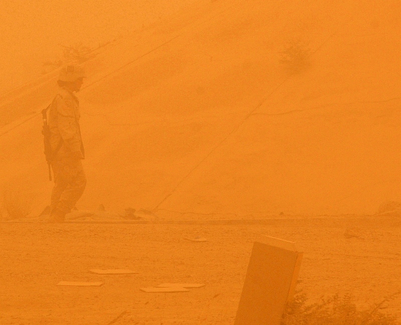 11. A United States Army Soldier (42nd Infantry Division) Conducts a Post-Attack Reconnaissance Sweep During a Big Sandstorm, July 14, 2005, Balad Air Base, Al Jumhuriyah al Iraqiyah - Republic of Iraq. Photo Credit: Staff Sgt. (SSgt) Chad Chisholm, United States Air Force (USAF, http://www.af.mil); Army Images (http://www4.army.mil/armyimages, U.S. Army Image ID: CSA-2005-07-22-091514), USAF Image ID: 050714-F-9209C-002; Photo Courtesy of United States Army (U.S. Army, http://www.army.mil), United States Department of Defense (DoD, http://www.DefenseLink.mil or http://www.dod.gov), Government of the United States of America (USA).