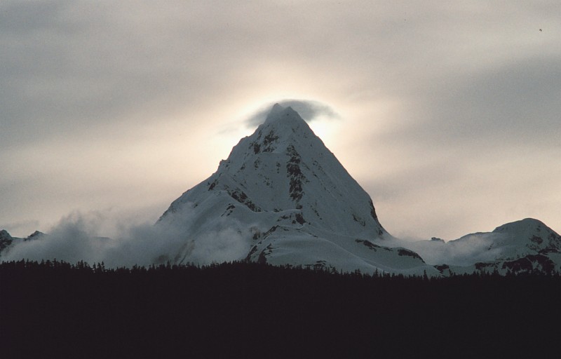 High, Majestic, Sharp, Snow-Covered Mountain Peak With a Small Cloud at the Top, June 1992, State of Alaska, USA. Photo Credit: Commander John Bortniak, NOAA Corps; National Oceanic and Atmospheric Administration Photo Library (http://www.photolib.noaa.gov, corp1967), NOAA Corps Collection, NOAA Central Library, National Oceanic and Atmospheric Administration (NOAA, http://www.noaa.gov), United States Department of Commerce (http://www.commerce.gov), Government of the United States of America (USA).