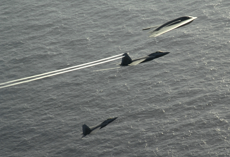 5. The B-2 Spirit and the Two F-22A Raptor Fighter Jets -- the Center Aircraft, An F-22A Raptor, With Trailing Vortices -- Flying In Formation Over the Pacific Ocean, April 14, 2009, Territory of Guam, USA. Photo Credit: Master Sgt. Kevin J. Gruenwald, United States Air Force (USAF, http://www.af.mil); Defense Visual Information (DVI, http://www.DefenseImagery.mil, 090414-F-6911G-005) and United States Air Force (USAF, http://www.af.mil), United States Department of Defense (DoD, http://www.DefenseLink.mil or http://www.dod.gov), Government of the United States of America (USA).