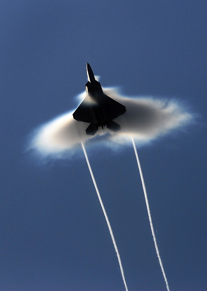 1. Condensation Cloud and Trailing Vortices: A United States Air Force (USAF) F-22A Raptor Stealth Fighter Jet, June 22, 2009, High-Speed Flyby Above the United States Navy's (USN) Nimitz-Class Aircraft Carrier USS John C. Stennis (CVN 74) During Northern Edge 2009 in the Gulf of Alaska, State of Alaska, USA. Photo Credit: Mass Communication Specialist 3rd Class Josue L. Escobosa, United States Navy; Defense Visual Information (DVI, http://www.DefenseImagery.mil, 090622-N-9928E-216) and United States Navy (USN, http://www.navy.mil), United States Department of Defense (DoD, http://www.DefenseLink.mil or http://www.dod.gov), Government of the United States of America (USA).