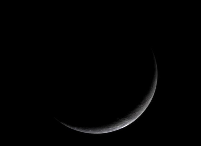 In the Dense Darkness of the Outer Solar System, Enceladus, One of Saturn's Moons, is Almost Invisible. Photo Credit: Cassini-Huygens Mission (http://saturn.jpl.nasa.gov), Cassini Orbiter, January 16, 2005; Planetary Photojournal (http://photojournal.jpl.nasa.gov, PIA06579), National Aeronautics and Space Administration (NASA, http://www.nasa.gov)/Jet Propulsion Laboratory (JPL, http://www.jpl.nasa.gov)/Space Science Institute (http://ciclops.org), Government of the United States of America.