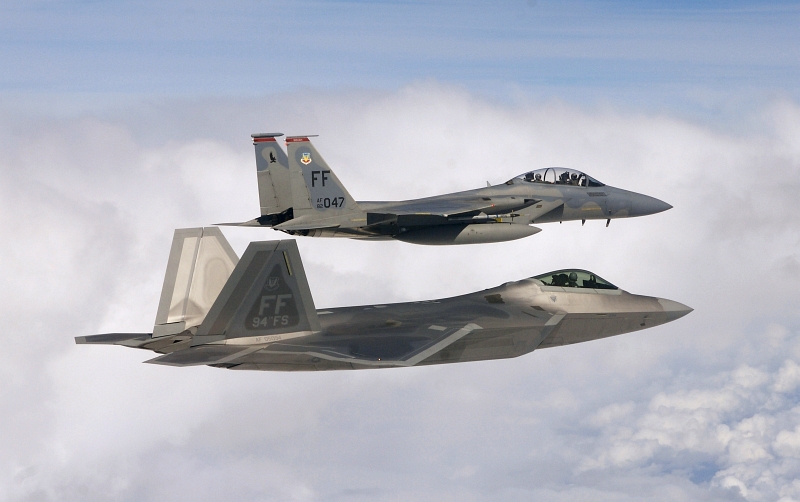 19. A USAF F-22A Raptor Stealth Fighter Jet Flies In Formation With A F-15 Eagle Fighter Jet, October 18, 2007, Off the Coast of the State of North Carolina, USA. The F-15 Eagle (top) is piloted by USAF Capt. Bradley Brumbaugh (71st Fighter Squadron) with Bill Weir (a co-anchor for ABC's 'Good Morning America' show) in the back seat. The USAF F-22A Raptor (bottom) is piloted by USAF Capt. Greg Priesser (94th Fighter Squadron). Photo Credit: Staff Sgt. Samuel Rogers, United States Air Force; Defense Visual Information (DVI, http://www.DefenseImagery.mil, 071018-F-WB275-055) and United States Air Force (USAF, http://www.af.mil), United States Department of Defense (DoD, http://www.DefenseLink.mil or http://www.dod.gov), Government of the United States of America (USA).