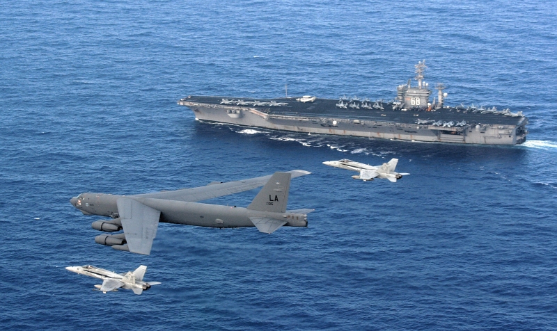 5. Two U.S. Navy F/A-18 Hornet Fighter Jets Intercept the Low-Flying U.S. Air Force B-52 Stratofortress Heavy Bomber As the Bomber Performs A Rigging Maneuver to Identify the Aircraft Carrier USS Nimitz (CVN 68), April 23, 2008. Photo Credit: Tech. Sgt. Corey Clements, United States Air Force; Defense Visual Information (DVI, http://www.DefenseImagery.mil, 080423-F-OJ435-003) and United States Air Force (USAF, http://www.af.mil), United States Department of Defense (DoD, http://www.DefenseLink.mil or http://www.dod.gov), Government of the United States of America (USA).