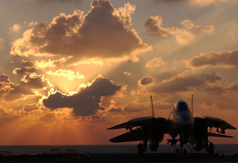 In the Persian Gulf: Cloud-Filled Sky Painted In Shades of Gold and Orange Hues, Sunbeams Streaming From Behind the Cloud That's Blocking the Sun -- It's a Beautiful, Pleasureable, and Wonderful Scene on January 15, 2006, Witnessed From Aboard the United States Navy Aircraft Carrier USS Theodore Roosevelt (CVN 71). Lower Right: A Parked F-14D Tomcat Fighter Jet Assigned to the 'Tomcatters' of Fighter Squadron Three One (VF-31). Photo Credit: Lithographer's Mate 3rd Class Jonathan Snyder, Navy NewsStand - Eye on the Fleet Photo Gallery (http://www.news.navy.mil/view_photos.asp, 060115-N-7571S-002), United States Navy (USN, http://www.navy.mil), United States Department of Defense (DoD, http://www.DefenseLink.mil or http://www.dod.gov), Government of the United States of America (USA).