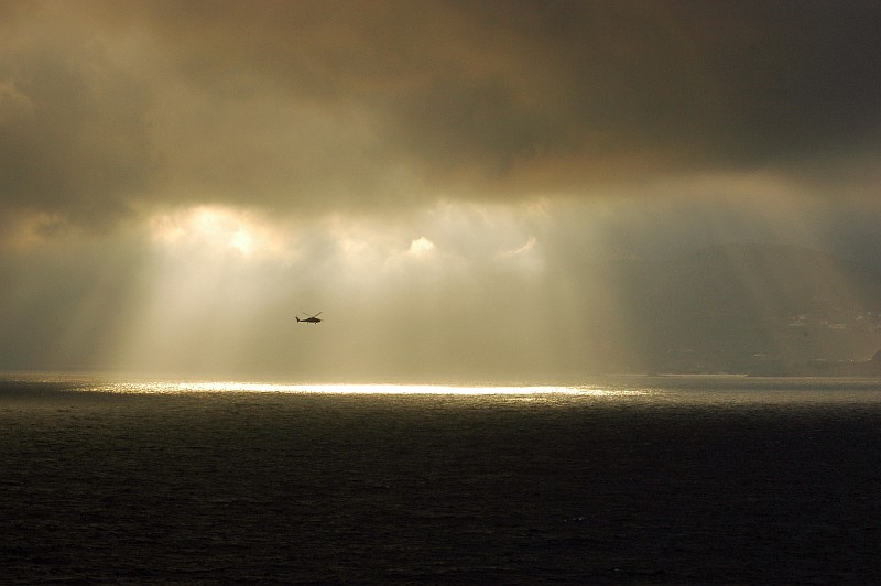 Sunlight Pushes Through the Clouds Spreading, Shining, and Focusing a Soft, Beautiful, Golden Curtain-of-Light Over and On the Waters of the Strait of Gibraltar (Straits of Gilbraltar) in the Mediterranean Sea. Gibraltar, Overseas Territory of the United Kingdom of Great Britain and Northern Ireland. Photo Credit: Mass Communication Specialist 2nd Class Miguel Angel Contreras, Navy NewsStand - Eye on the Fleet Photo Gallery (http://www.news.navy.mil/view_photos.asp, 061014-N-0490C-005), United States Navy (USN, http://www.navy.mil), United States Department of Defense (DoD, http://www.DefenseLink.mil or http://www.dod.gov), Government of the United States of America (USA).