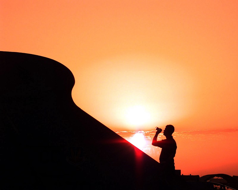 Desert Sunset: He Takes a Sip of Water as the Sun Sets Over Prince Sultan Air Base, Al Mamlakah al Arabiyah as Suudiyah - Kingdom of Saudi Arabia. Photo Credit: Airman First Class (A1C) Greg L. Davis, 1st Combat Camera Squadron, United States Air Force; Defense Visual Information Center (DVIC, http://www.DoDMedia.osd.mil, DFSD0317373 and 980401F7910D009) and United States Air Force (USAF, http://www.af.mil), United States Department of Defense (DoD, http://www.DefenseLink.mil or http://www.dod.gov), Government of the United States of America (USA).