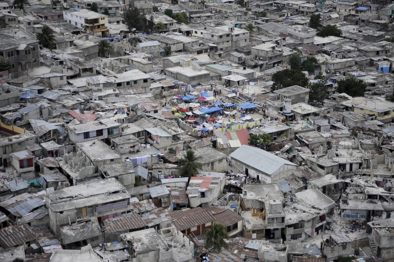 38. Earthquake Survivors In A Tent City, Surrounded By Houses Damaged By the Earthquake, January 19, 2010, Republique d'Haiti (Repiblik d' Ayiti) - Republic of Haiti. Photo Credit: Technical Sgt. (TSgt) Dennis J. Henry Jr., United States Air Force; Defense Visual Information (DVI, http://www.DefenseImagery.mil, 100119-F-3715H-182) and United States Air Force (USAF, http://www.af.mil), United States Department of Defense (DoD, http://www.DefenseLink.mil or http://www.dod.gov), Government of the United States of America (USA).