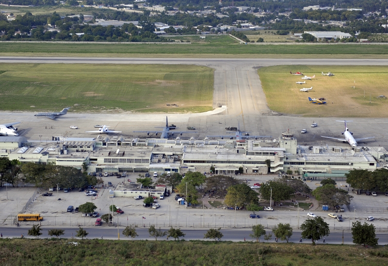 49. Aerial View of Cars, Trucks, A Yellow School Bus, Civilian and Military Aircraft At Toussaint Louverture International Airport, January 23, 2010, Republique d'Haiti (Repiblik d' Ayiti) - Republic of Haiti. Photo Credit: Staff Sgt. Desiree N. Palacios, Air Force Link (AFLink) Photos (http://www.af.mil/photos, 100123-F-1830P-263, 'Combat controllers at work'), United States Air Force (USAF, http://www.af.mil), United States Department of Defense (DoD, http://www.DefenseLink.mil or http://www.dod.gov), Government of the United States of America (USA).