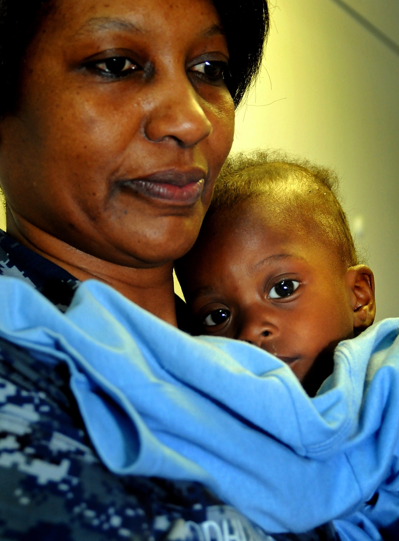 44. United States Navy Religious Programs Specialist 1st Class Lunar Odhiambo Holds An Injured Haitian Child -- A Victim of the Magnitude-7.0 Earthquake -- In Her Arms and Comforts Him As He Recovers In the Medical Ward Aboard the U.S. Navy Multi-Purpose Amphibious Assault Ship USS Bataan (LHD 5), January 21, 2010, Baie de Grand Goave, Republique d'Haiti (Repiblik d' Ayiti) - Republic of Haiti.  Photo Credit: Mass Communication Specialist 3rd Class Samantha Robinett, Navy News Service - Eye on the Fleet (http://www.news.navy.mil/view_photos.asp, 100121-N-5808R-075), United States Navy (USN, http://www.navy.mil), United States Department of Defense (DoD, http://www.DefenseLink.mil or http://www.dod.gov), Government of the United States of America (USA).